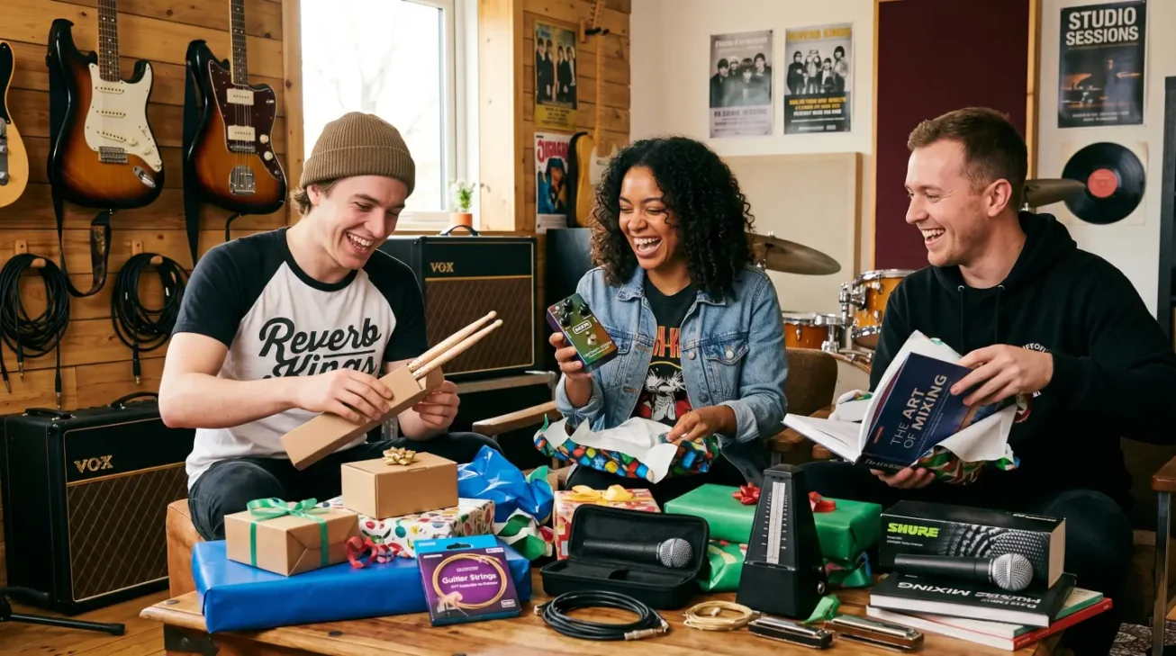 Drei Musiker freuen sich über Geschenke für Musiker wie Drumsticks, Effektpedal, Mikrofon, Metronom, Kabel und Musikbücher.